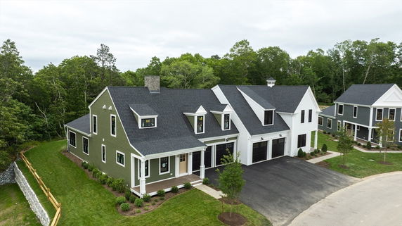 Front view of a large two-story house with a double garage and green exterior.