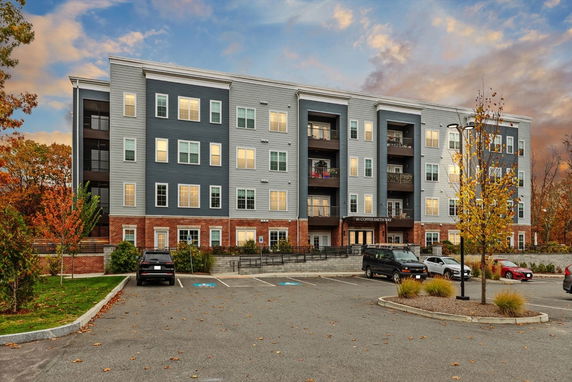 Front view of a multi-story apartment building with brick and siding exterior.