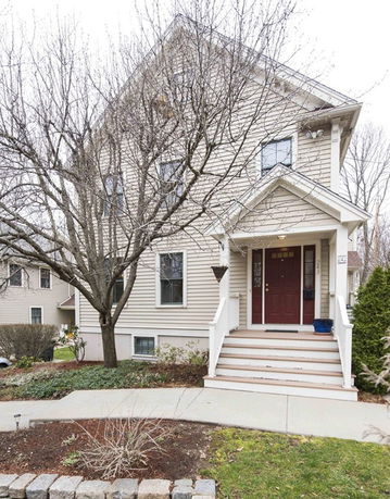 Front view of a two-story house with a gable roof and front porch.