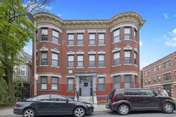 Front view of a three-story red brick building with bay windows.