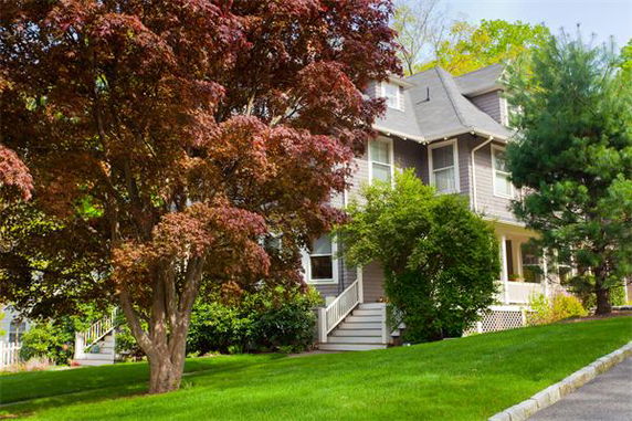 Front view of a multi-story house with a porch and steep roof.