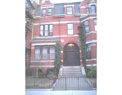 Front view of a multi-story brick building with arched entrance and ivy-covered facade.