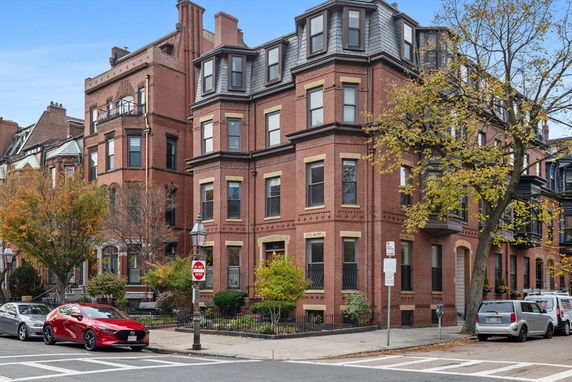 Front view of a multi-story brick building with bay windows and decorative trim.