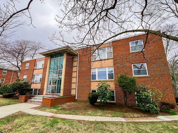 Front view of a three-story brick apartment building with large glass entrance.