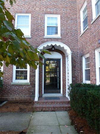Front view of a brick building with an arched entrance and three windows.