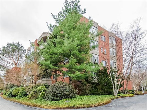 Front view of a multi-story brick building surrounded by trees.