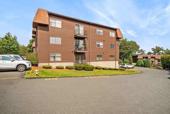 Front view of a multi-story apartment building with brown exterior and small balconies.
