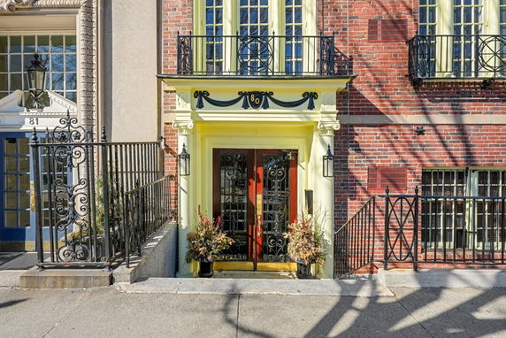 Front view of a brick building with ornate iron railings and decorative entrance.