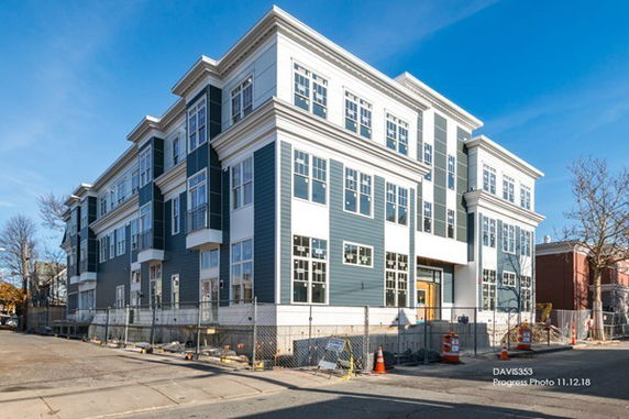 Front view of a multi-story residential building under construction with blue and white siding.