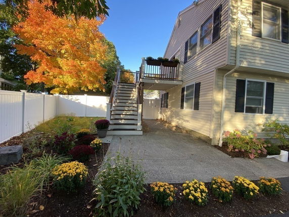 Side view of a house with an external staircase and landscaped garden.