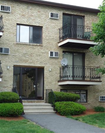 Front view of a multi-story brick building with balconies and a main entrance.