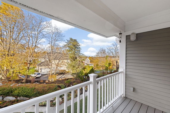 View from a balcony overlooking a residential neighborhood with houses and trees.