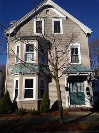 Front view of a two-story house with gabled roof and bay windows.
