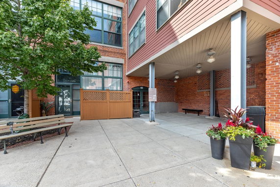 Front view of a brick residential building with large windows and an entrance under a covered area.