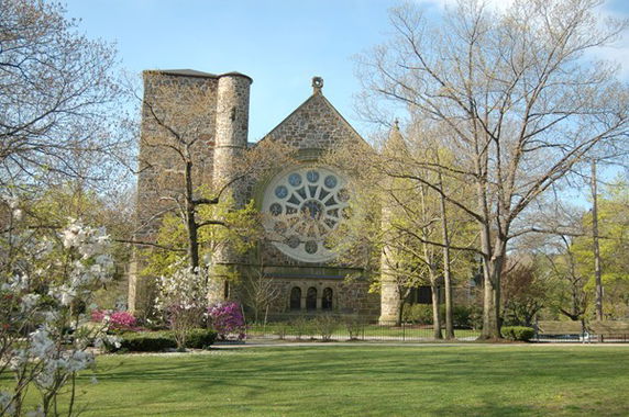 Front view of a stone building with circular stained glass window and towers.
