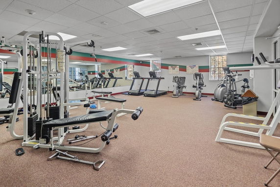 Gym area with various exercise equipment including treadmills and weight machines.