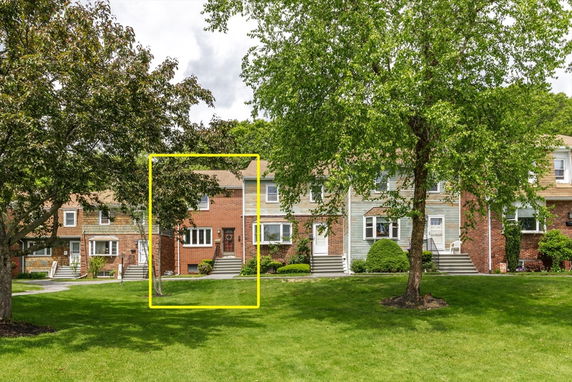 Front view of a row of townhouses with different exterior finishes including brick and siding.