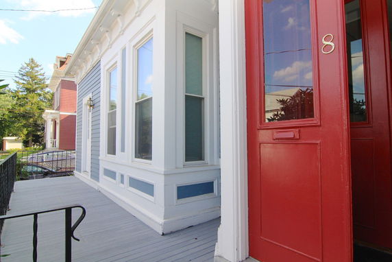Front view of a house with a red entrance door and sash windows.