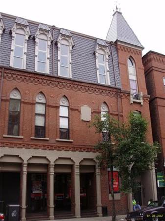 Front view of a multi-story brick building with decorative windows and a pointed roof.