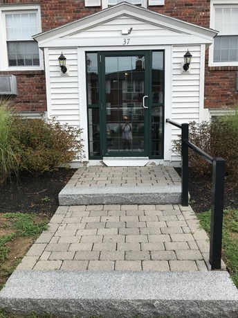 Front view of a house entrance with a glass door and white siding.