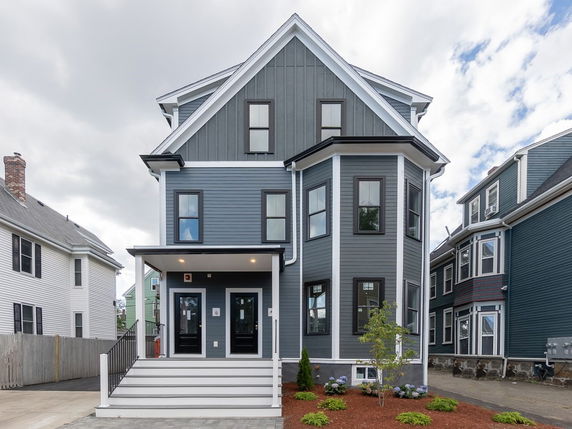 Front view of a multi-story house with blue siding and a covered porch.