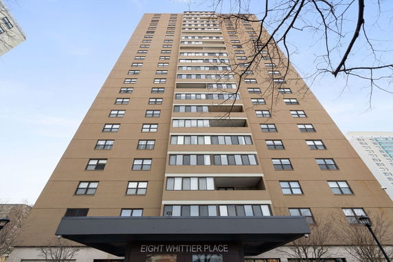 Front view of a tall residential building with multiple balconies and windows.