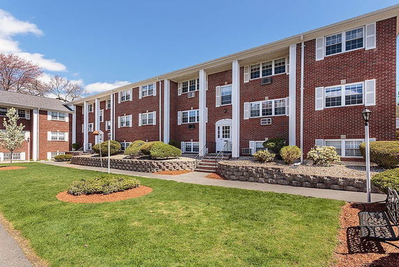 Front view of a three-story brick apartment building with white columns and windows.