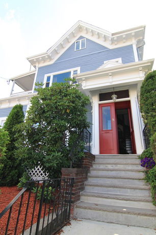 Front view of a multi-story house with red door and steps leading up.