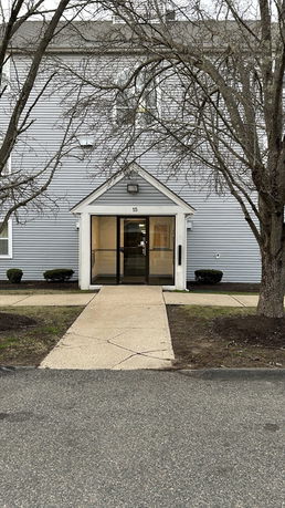 Front view of a building entrance with a pathway leading to double glass doors.