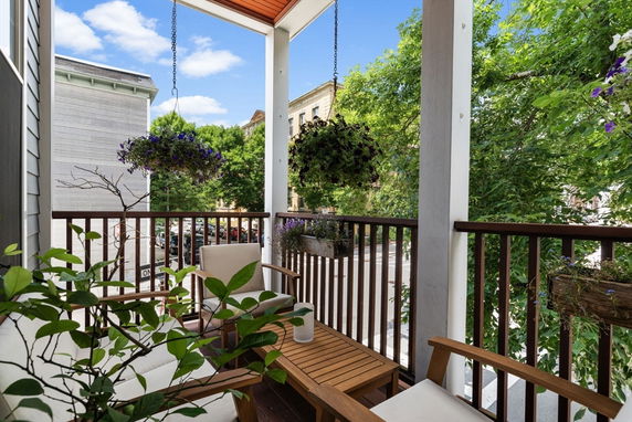 Balcony view with seating area overlooking trees and nearby buildings.