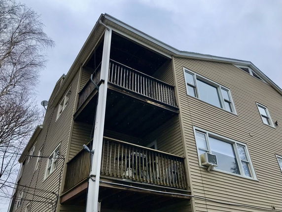 Side view of a multi-story building with wooden balconies.