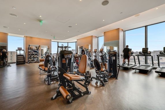 Gym area with various exercise equipment and large windows.