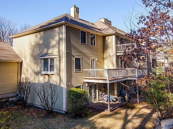 Rear view of a multi-story house with balconies and a chimney.