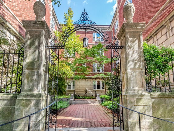 Front view of a brick building with ornate iron gates and stone pillars.