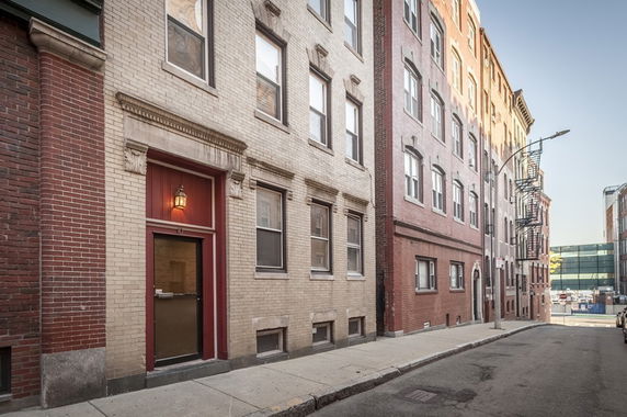Front view of a multi-story brick apartment building with a red entrance door.