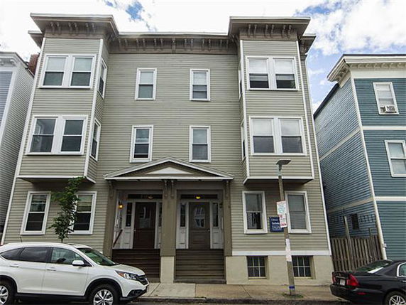 Front view of a three-story residential building with multiple windows and two entrance doors.