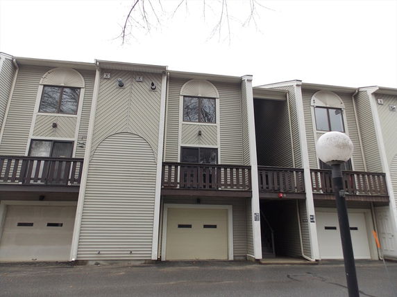 Front view of a multi-story building with garages beneath and balconies above.