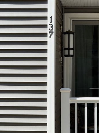 Close-up of a house exterior showing part of the front with siding and a porch light.