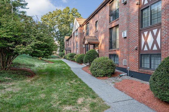 Front view of a multi-story brick building with large windows and landscaped pathway.