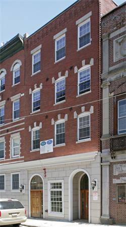 Front view of a multi-story brick building with multiple windows and arched entrances.