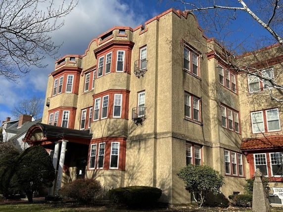 Front view of a multi-story building with red trim and multiple windows.