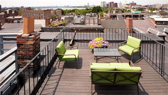 Rooftop terrace with seating area and view of surrounding cityscape.
