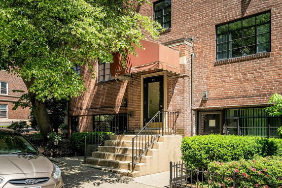 Front view of a brick building entrance with a staircase and canopy.