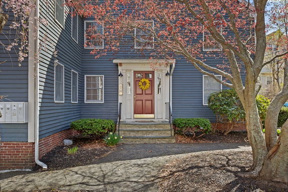 Front view of a house with blue siding and a red door, adorned with a wreath.