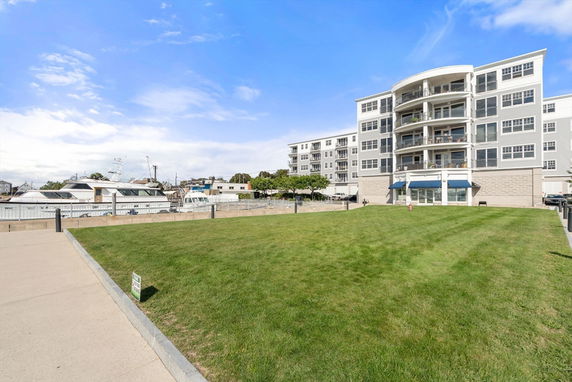 Front view of a multi-story apartment building with a grassy lawn area.