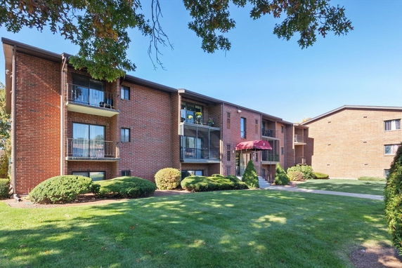 Front view of a multi-story brick apartment building with balconies.