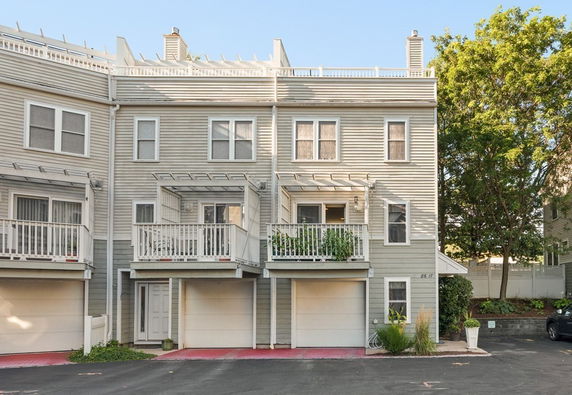 Front view of a multi-story townhouse with balconies and garages.