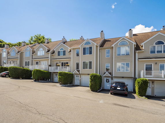 Front view of attached multi-story townhouses with garages.