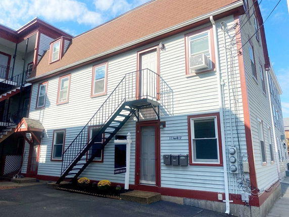 Front view of a two-story house with a gable roof and external staircase.