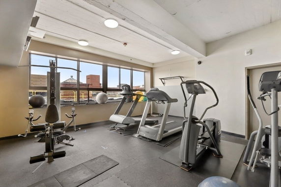 Indoor gym area with exercise equipment and large windows.